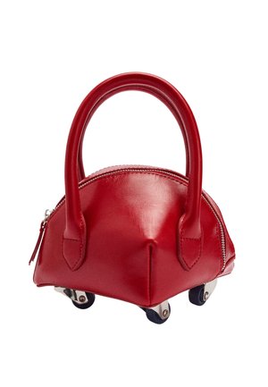 Czerwona skórzana torba o zaokrąglonym kształcie, z krótkimi uchwytami i kółkami. Posiada zamek błyskawiczny na górze i gładką teksturę. Wyróżnia się srebrnymi akcentami.
