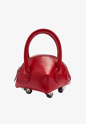 Czerwona skórzana torba o zaokrąglonym kształcie, z krótkimi uchwytami i kółkami. Posiada zamek błyskawiczny na górze i gładką teksturę. Wyróżnia się srebrnymi akcentami.