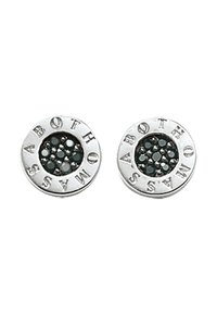 Orecchini rotondi in tono argento con lettering in rilievo e un centro in pietra scura incastonato con pietre più piccole, che mostrano una finitura testurizzata.