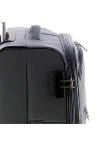 Grijze reistas met een gladde textuur, een zijgreep en een telescopische handgreep. Voorzien van een dubbele rits en een slank, rechthoekig ontwerp.