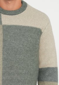 Maglione lavorato a maglia con scollo rotondo, motivo a blocchi in tonalità di verde e beige, con una texture morbida e collo a coste.