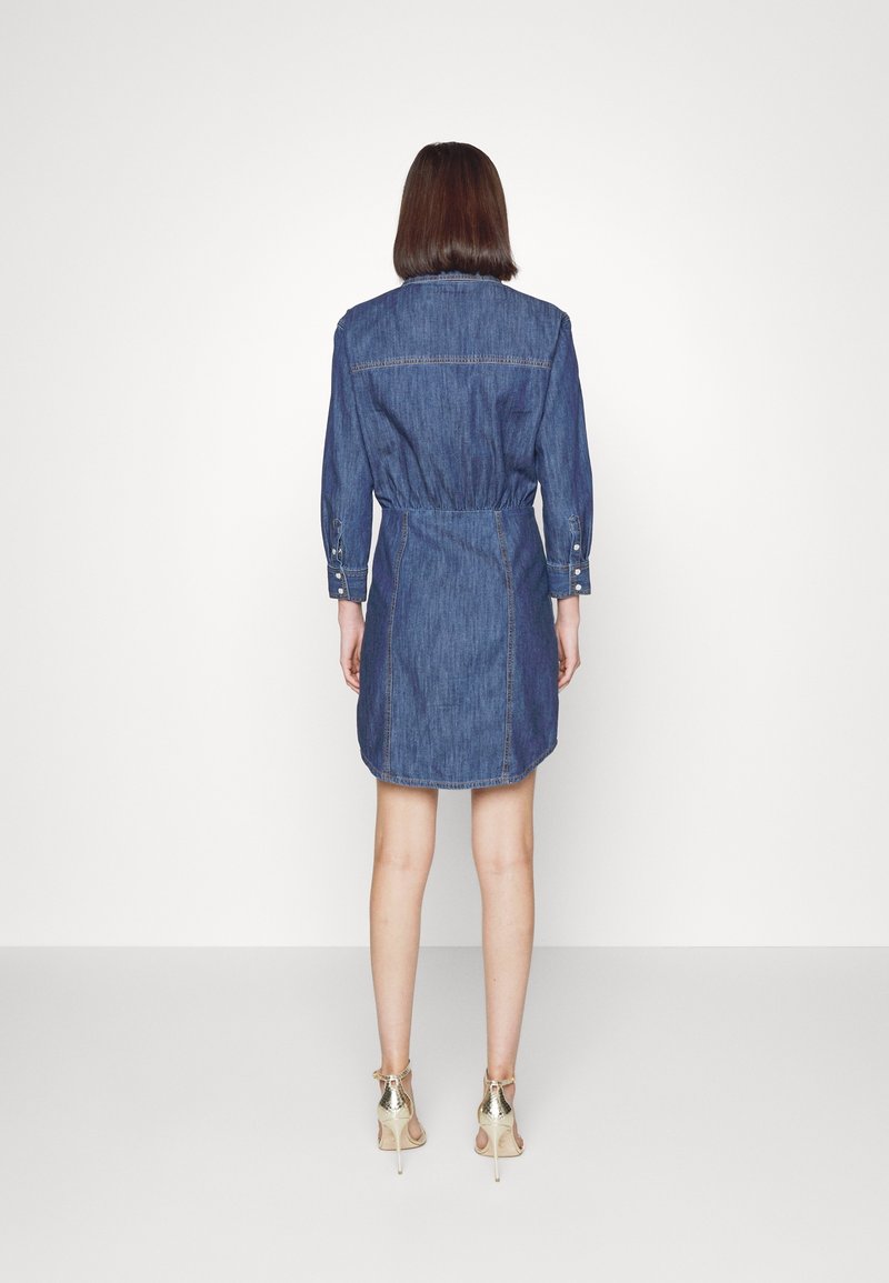 Denimová košilová šaty s dlouhými rukávy, staženým pasem a knoflíkovými detaily. Tkanina je tmavě modrá s hladkou texturou.
