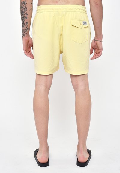 Pantaloni da bagno gialli realizzati in tessuto leggero, con vita elasticizzata, tasca posteriore con bottone e texture liscia.