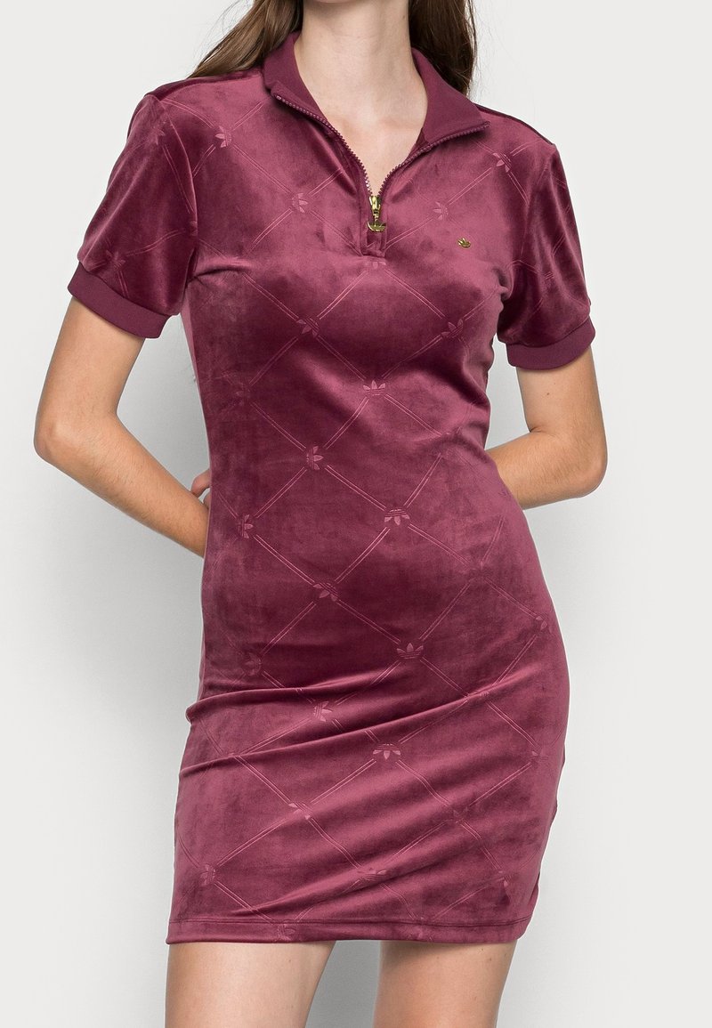 Short burgundy dress made of soft velvet, featuring a zippered collar, short sleeves, and a subtle embossed pattern across the fabric.