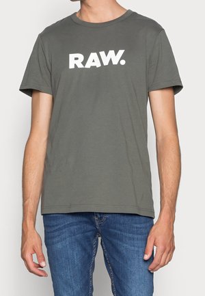 Bawełniany t-shirt w oliwkowej zieleni z krótkimi rękawami i okrągłym dekoltem, z widocznym białym logo "RAW." na przodzie.