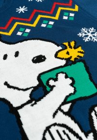 Maglione lavorato a maglia di colore blu, con un cane bianco che tiene un regalo verde. Il motivo include un pulcino giallo, fiocchi di neve e design zigzag colorati.