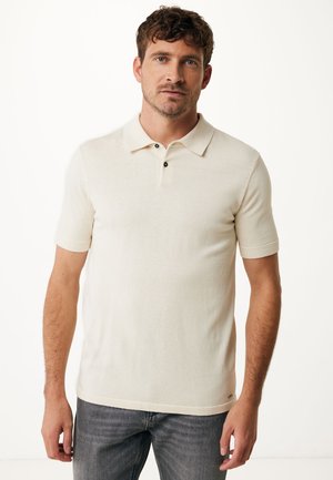 Beige kortærmet polo-shirt med krave, tre-knaps lukning, glat tekstur og diskret logo detalje ved kanten.