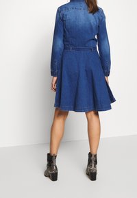 Jeanshemd jurk in een donkerblauwe tint, met een aansluitend lijfje, een uitlopende rok, lange mouwen en een ceintuur in de taille. Textuurstof met zichtbare naden.