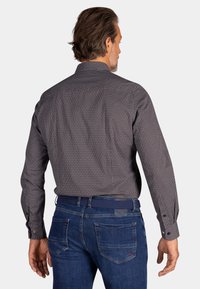 Langsleeve shirt in marineblauw met een wit, herhalend stippenpatroon, voorzien van een kraag en knopenmanchetten, gecombineerd met blauwe denim jeans.