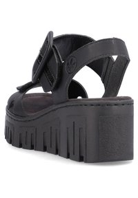 Sandales noires à plateforme avec une semelle épaisse, des brides en cuir, une boucle ajustable et un design découpé. Texturées, avec un pied plat et des accents surélevés.