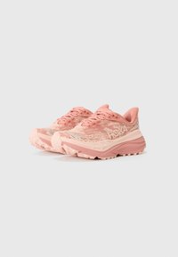 Chaussures de trail en rose clair. Tige en mesh avec des accents texturés, semelle intermédiaire rembourrée et semelle extérieure robuste pour une traction optimale.