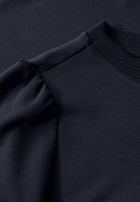 Sweatshirt bleu marine avec une finition texturée, doté d'un col côtelé et de manches bouffantes froncées pour un détail supplémentaire.