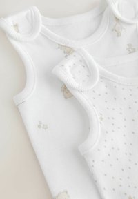 To hvide babyveste med forskellige designs: den ene med et diskret dyreprint og stjerner, den anden med et prikker mønster. Blødt bomulds materiale.
