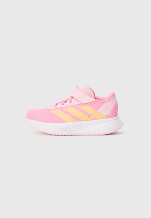 Chaussure de sport rose pour enfant avec des bandes jaunes, fermeture à lacets, sangle ajustable à scratch et semelle blanche rembourrée.