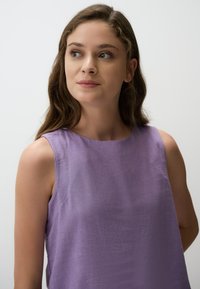 Paarse mouwloze top, gemaakt van een lichtgewicht stof met een zachte textuur. Rond decolleté en een relaxte pasvorm. Eenvoudig en strak design.