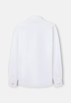 Camisa blanca de manga larga con botones vista desde atrás, con cuello clásico y puños abotonados sobre un fondo claro.