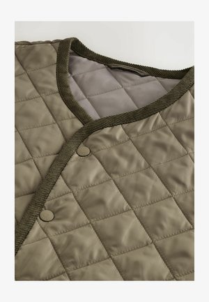 Veste matelassée dans un vert olive atténué avec une bordure côtelée vert foncé et une fermeture à boutons. Le tissu a une texture lisse et brillante.