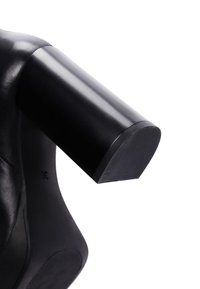 Zwarte leren schoen met een afgeronde blokhak. De hak heeft een platte basis met een textuur voor grip. Gladde algehele afwerking.