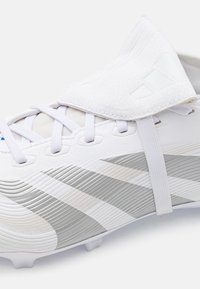 Gheat de fotbal alb cu accente argintii, superior texturat, închidere cu şireturi şi clapetă plisată. Prezintă un design proeminent cu trei dungi.
