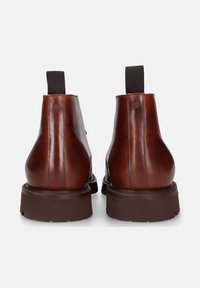 Braune Leder-Stiefeletten mit elastischen Seitenpanelen und einer strukturierten Gummisohle. Glatte Oberfläche mit runder Zehenpartie und robuster Bauweise.