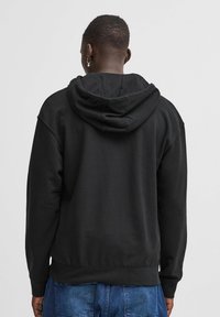 Black hooded sweatshirt with a relaxed fit, ribbed cuffs, and waistband, featuring a textured fabric and a center-back seam detail.