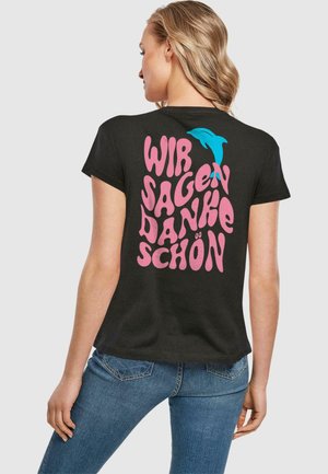 Sort bomulds-T-shirt med stor lyserød tekst på ryggen: "WIR SAGEN DANKE SCHÖN," med en lille blå delfin som accent over teksten.