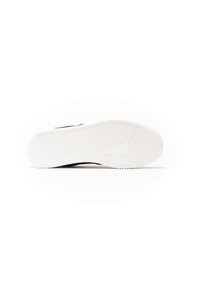 Suola di scarpe in gomma bianca con motivo di presa texturizzato e logo. Design con cresta centrale e bordo liscio per supporto ergonomico.