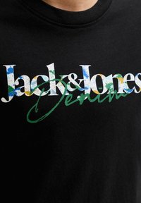 Μαύρο μπλουζάκι με το "Jack & Jones" σε πολύχρωμα γράμματα και το "Denim" γραμμένο με πράσινη γραμματοσειρά στο στήθος.