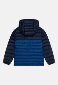Marinblå pufferjacka med huva, med ett horisontellt quiltat mönster, kontrasterande ljusare och mörkare blå sektioner, slät yta och elastiska muddar.