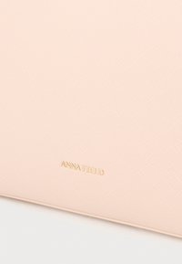 Rózsaszín texturált pénztárca szintetikus anyagból, aranyozott dombornyomott logóval, téglalap alakú, sima felülettel.