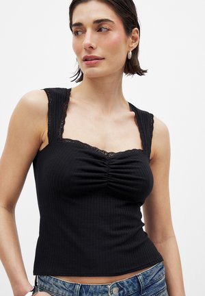 Black ribbed tank top with lace details at the straps and neckline, featuring a gathered front design. Casual fit with a cropped length.