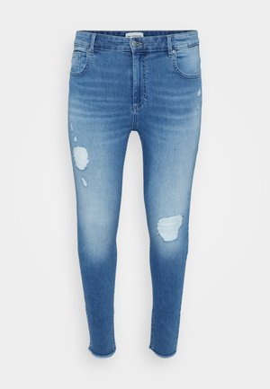 Jasnoniebieskie wąskie dżinsy z przetartymi łatami z przodu, o średnim stanie i standardowym pięcio-kieszonkowym kroju, wyeksponowane na neutralnym tle.