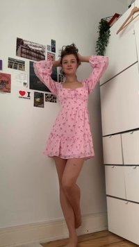 Vestido floral rosa com mangas bufantes longas, decote quadrado e saia rodada com babados. Tecido suave com delicados padrões de flores.