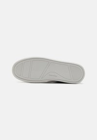 Hvit sneakersåle med teksturerte grep mønstre og et Calvin Klein-logo. Glatt finish. Designet for komfort og holdbarhet.