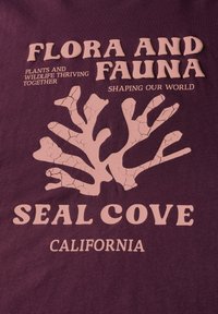 Bordová tričko s bledě růžovým textem a korálovým designem. Text zahrnuje "FLORA A FAUNA," "SEAL COVE," a "CALIFORNIE."