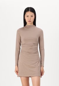 Langermet, tettsittende kjole i lys brun, laget av et glattet, elastisk stoff med sidefolding og høy mock-neck.