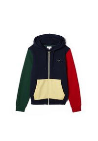 Mörkblå zip-hoodie med mörkgrön vänsterärm, röd högerärm, beige frontfickor och en liten grön krokodil-logotyp på bröstet.