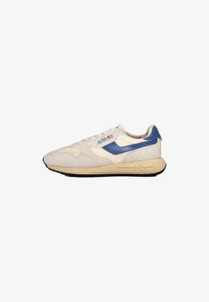 Chaussure de sport beige et crème avec des accents bleus, des lacets blancs et un logo du drapeau américain sur le côté, dotée d'une semelle beige avec des détails en forme d'étoiles.