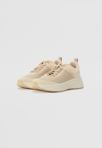 Baskets de sport beige avec une tige en mesh, un design de soutien, des accents texturés, une semelle rembourrée et des lacets ton sur ton ; forme légère et moderne.