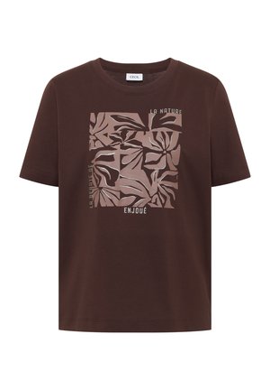T-shirt marron à manches courtes avec un motif de feuilles abstraites en beige et les mots français "La Nature", "La Revue de" et "Enjoué" sur le devant.