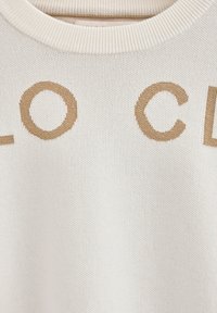 Cremefarbener Strickpullover mit großen, gewebten beigen Buchstaben, die "LOCAL" auf der Vorderseite schreiben. Gerippter Halsausschnitt und Bündchen. Weiche Textur.