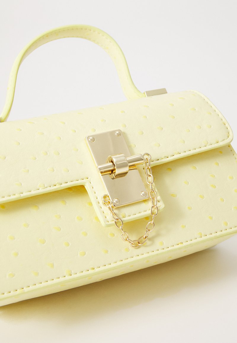 Sac à main en simili cuir jaune avec des pois texturés, quincaillerie dorée et accent de chaîne. Comprend une poignée supérieure structurée et une fermeture à rabat.