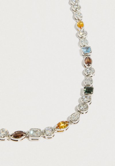 Naszyjnik w odcieniu srebra z naprzemiennie ułożonymi kamieniami o geometrycznych i unikalnych kształtach w przezroczystych, niebieskich, zielonych, bursztynowych i brązowych odcieniach.