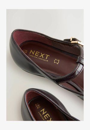 Schwarze Lederballerinas mit gepolstertem Innenraum, einem goldenen Logo, verstellbarem Riemen und glatter Oberfläche. Geeignet für Freizeitbekleidung.