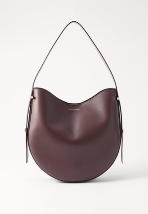 Sac à main en cuir bordeaux avec une forme incurvée, une fine bandoulière et des accents en métal doré, présentant un design minimaliste.