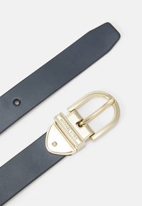 Ceinture en cuir bleu avec une boucle en métal doré portant un logo en relief. La sangle a une texture lisse et une pointe effilée.