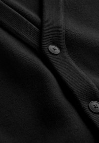 Sort cardigan med ribbet tekstur, sjalskrave og to sorte knapper. Stoffet ser blødt og glat ud med et raffineret design.