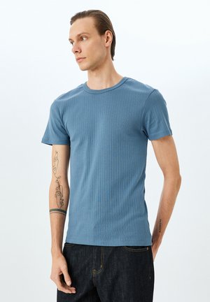 Blå ribbet T-shirt med korte ærmer, rund halsudskæring og en tætsiddende pasform. Har tekstureret stof og synlige syninger.