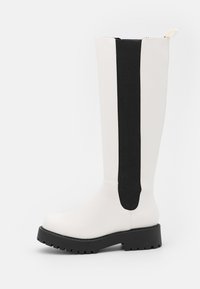 Botas altas até ao joelho, feitas de material sintético branco liso, com painéis laterais elásticos pretos, sola de borracha preta robusta e bico redondo.