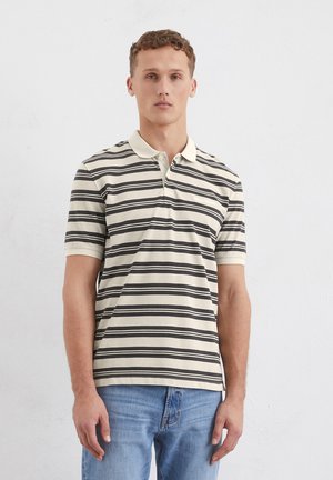Gestreepte polo met crème en zwarte strepen, met een kraag en twee knopen. Draagt met blauwe denim jeans. Korte mouwen, casual pasvorm.